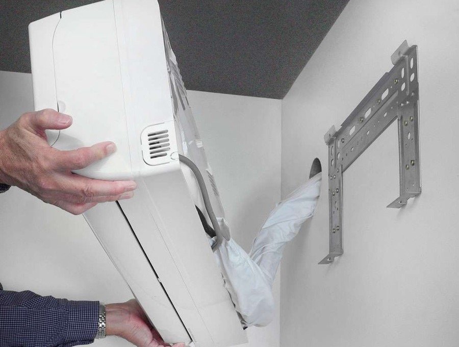 T&eacute;cnico instalando ar condicionado split no suporte de parede